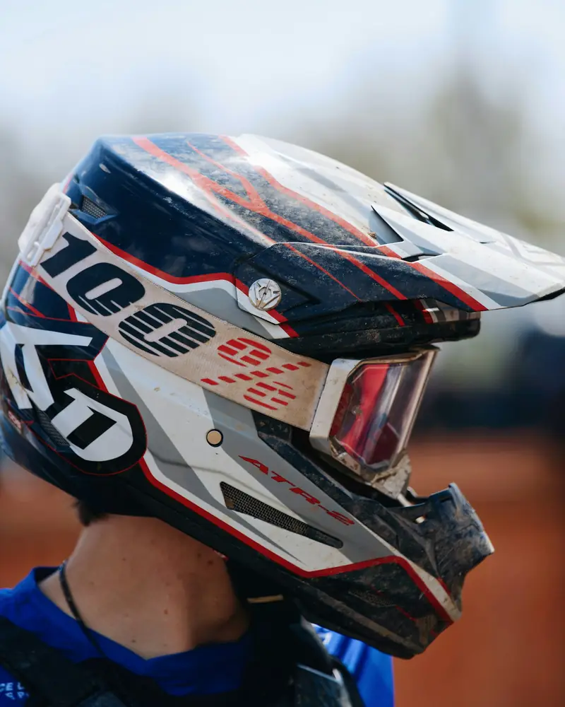 Piloto de motocross com capacete off-road branco, vermelho e azul
