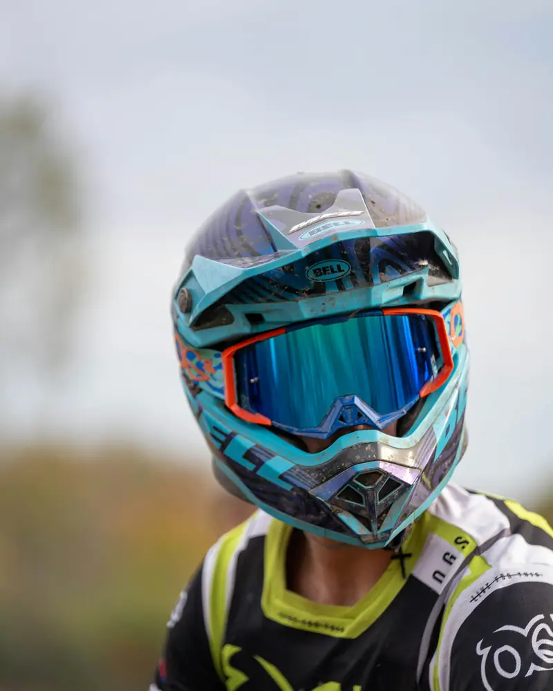 Piloto com capacete turquesa e óculos de lente espelhada